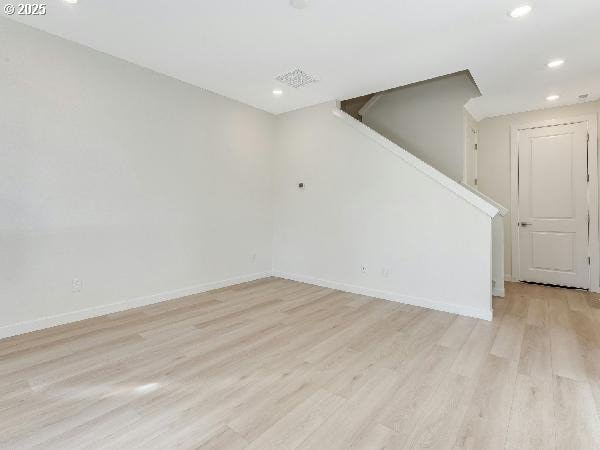 spare room with stairs, recessed lighting, light wood-type flooring, and baseboards