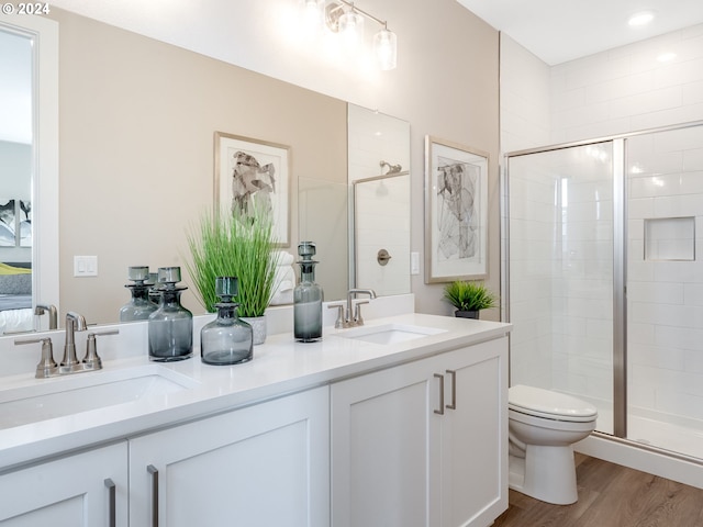 bathroom featuring hardwood / wood-style floors, vanity, a shower with shower door, and toilet