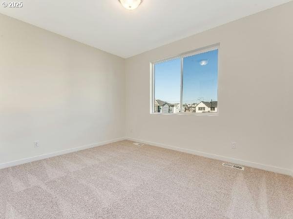 empty room with carpet, visible vents, and baseboards