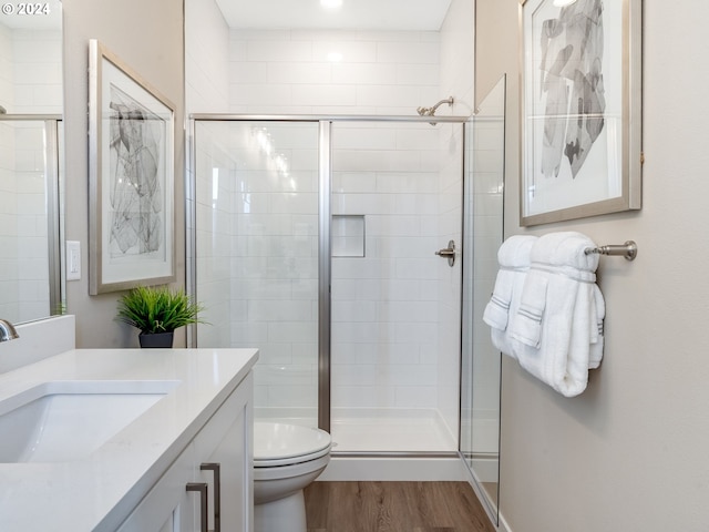 bathroom featuring vanity, hardwood / wood-style flooring, toilet, and walk in shower