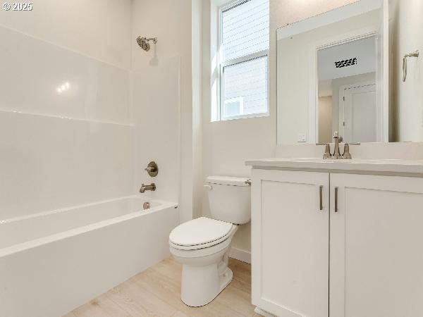 bathroom with toilet, tub / shower combination, wood finished floors, and vanity