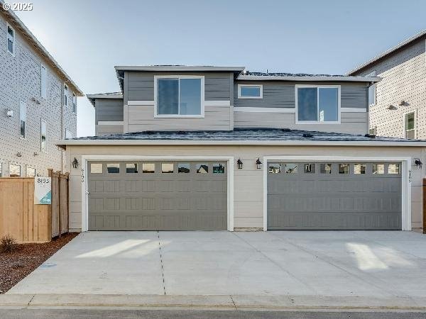 view of front facade featuring a garage, driveway, and fence