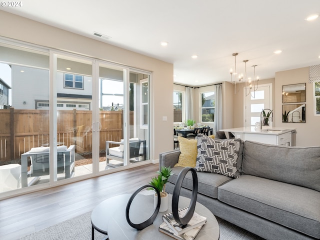 living room featuring plenty of natural light, a chandelier, and light wood-type flooring