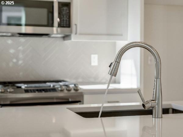 room details with white cabinetry, stainless steel appliances, and a sink