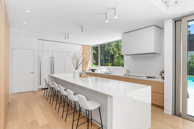 kitchen featuring a kitchen breakfast bar, a kitchen island, light hardwood / wood-style flooring, and white cabinetry