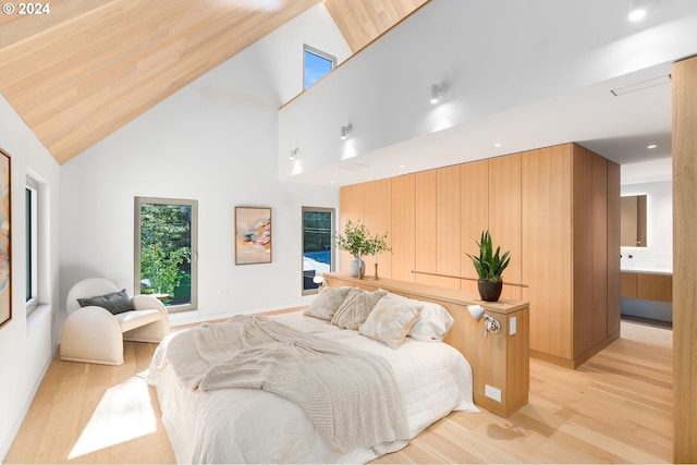 bedroom featuring ensuite bath, light hardwood / wood-style floors, and high vaulted ceiling