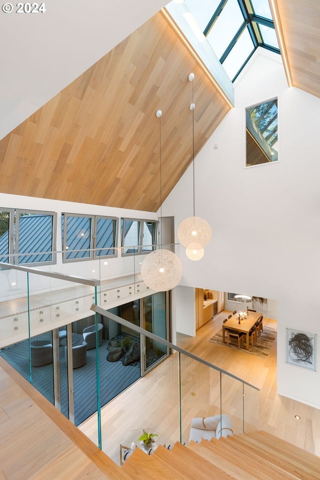 interior space with a skylight, high vaulted ceiling, hardwood / wood-style floors, and wood ceiling