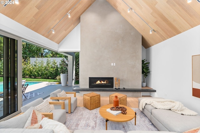 living room featuring wood ceiling, track lighting, high vaulted ceiling, and a large fireplace