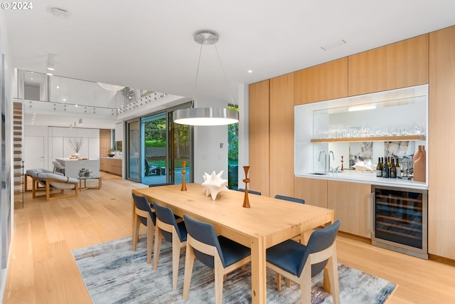 dining area featuring indoor wet bar, beverage cooler, and light hardwood / wood-style floors