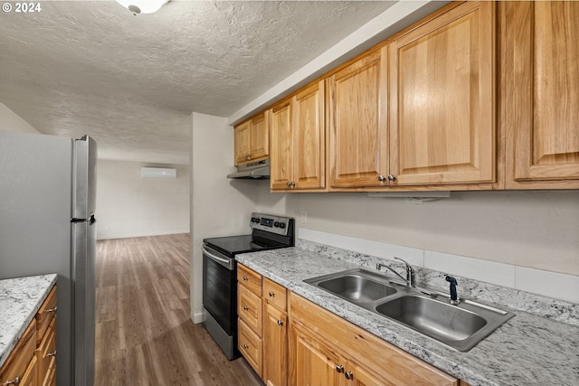 kitchen with sink, light stone counters, appliances with stainless steel finishes, a textured ceiling, and dark wood-type flooring