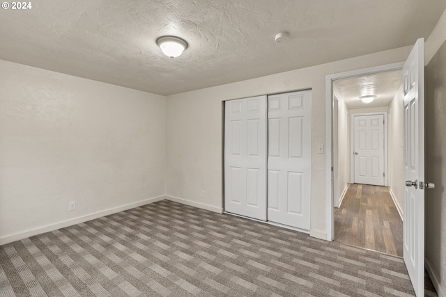 unfurnished bedroom featuring a closet, a textured ceiling, and light colored carpet