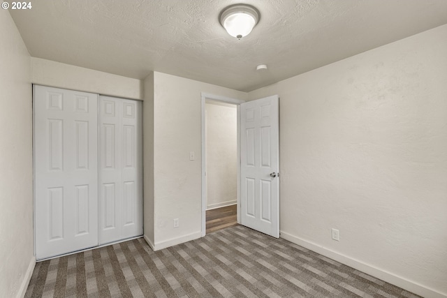 unfurnished bedroom with a closet, a textured ceiling, and carpet flooring