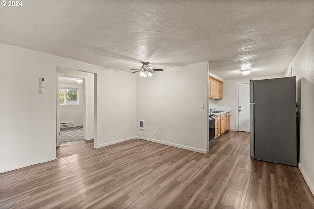 unfurnished living room with sink, ceiling fan, a textured ceiling, baseboard heating, and wood-type flooring