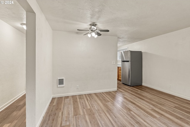 interior space featuring light wood-type flooring, a textured ceiling, ceiling fan, and heating unit