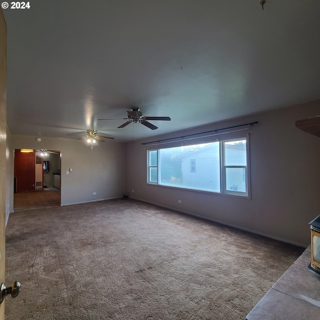 unfurnished living room with dark colored carpet and ceiling fan