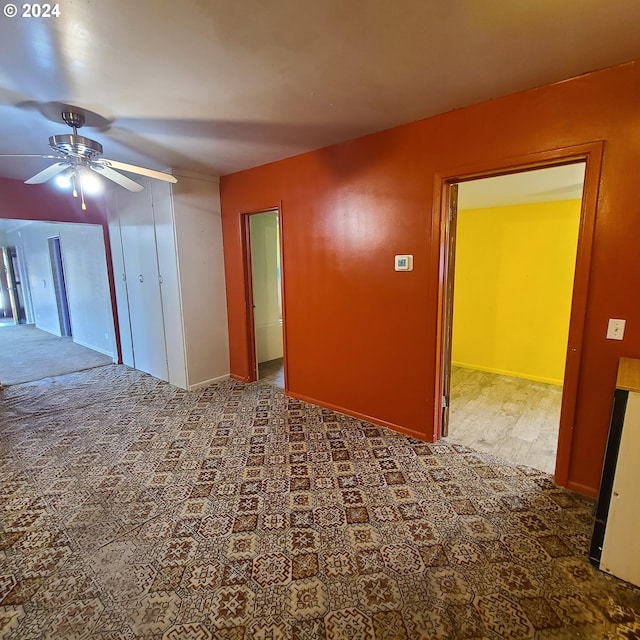 empty room with dark colored carpet and ceiling fan