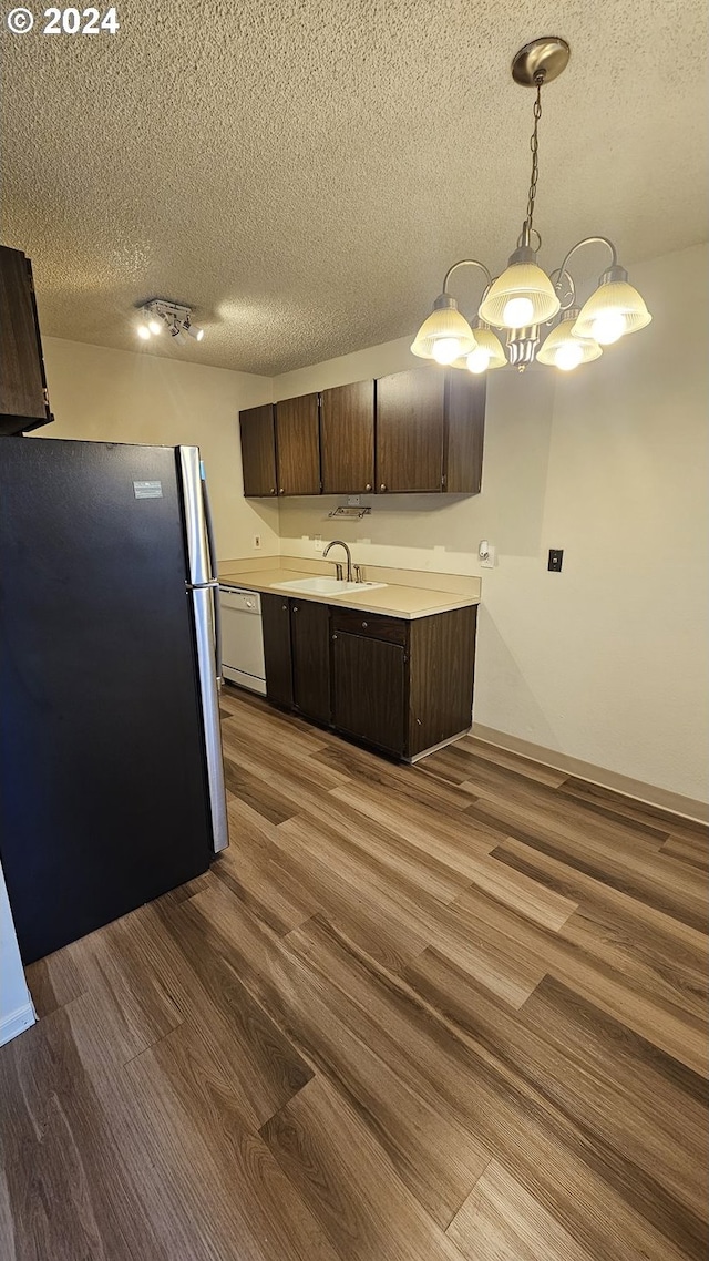 kitchen with dark brown cabinetry, stainless steel refrigerator, light hardwood / wood-style floors, and a textured ceiling