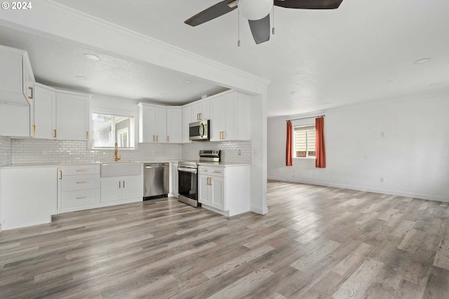 kitchen featuring a healthy amount of sunlight, appliances with stainless steel finishes, light hardwood / wood-style floors, and white cabinets