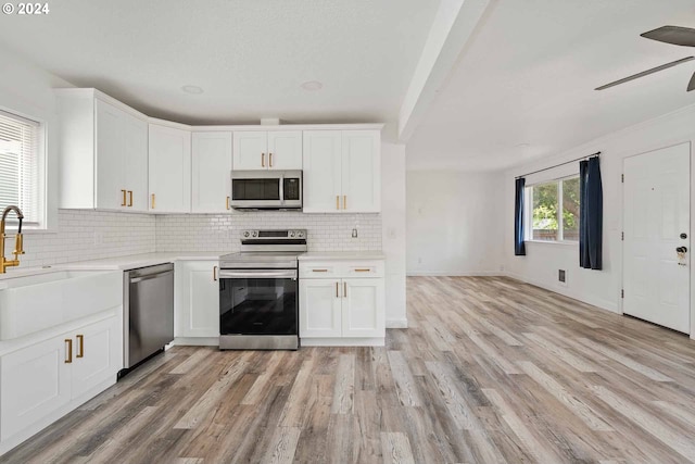 kitchen featuring white cabinets, ceiling fan, stainless steel appliances, and light hardwood / wood-style floors