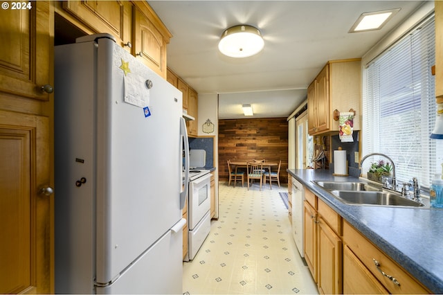 kitchen with sink, white appliances, and wood walls