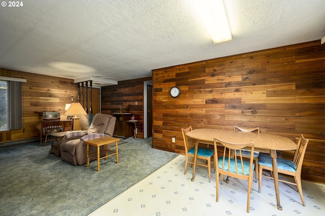 carpeted dining room with wood walls and a textured ceiling