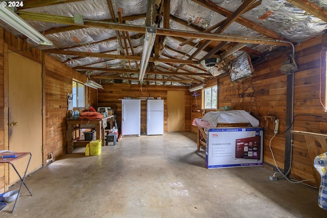 miscellaneous room with wooden walls, concrete floors, and vaulted ceiling