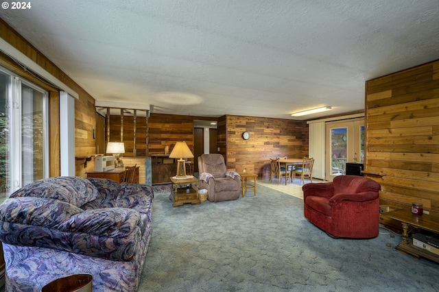 living room featuring wooden walls, french doors, carpet floors, and a textured ceiling