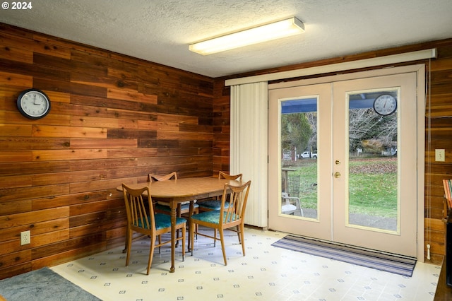 dining area with french doors and wood walls