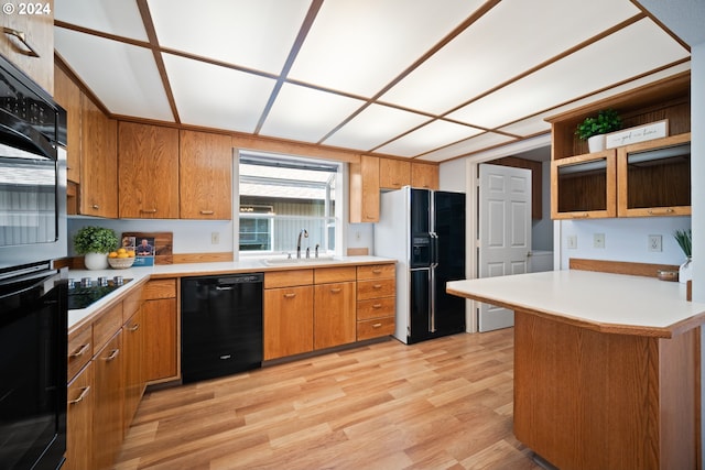 kitchen featuring kitchen peninsula, light wood-type flooring, sink, and black appliances