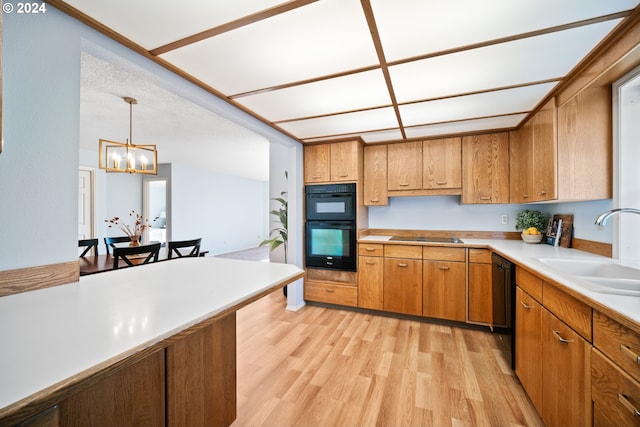 kitchen featuring black appliances, sink, hanging light fixtures, light hardwood / wood-style flooring, and a notable chandelier