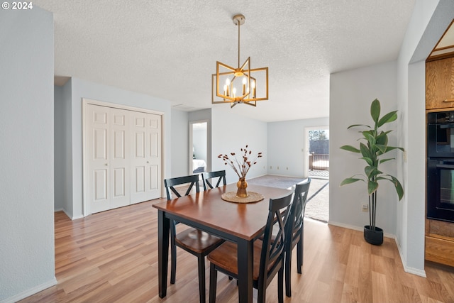 dining area featuring a textured ceiling, an inviting chandelier, and light hardwood / wood-style flooring