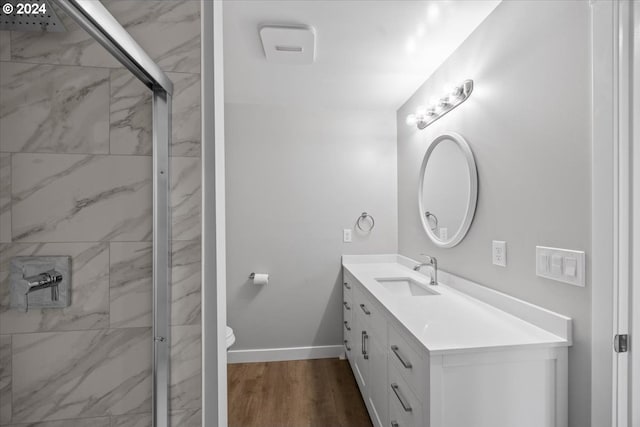 bathroom featuring hardwood / wood-style floors, vanity, a shower with door, and toilet