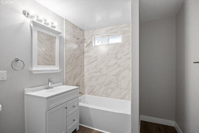 bathroom with hardwood / wood-style flooring, vanity, and tiled shower / bath