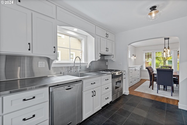 kitchen featuring appliances with stainless steel finishes, stainless steel counters, white cabinetry, and plenty of natural light