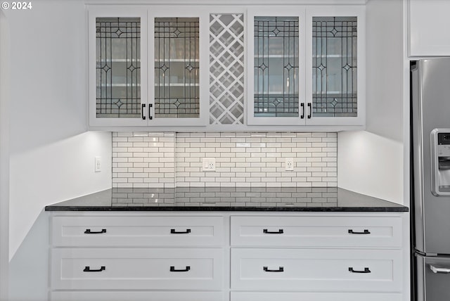 kitchen with stainless steel fridge, decorative backsplash, and white cabinets