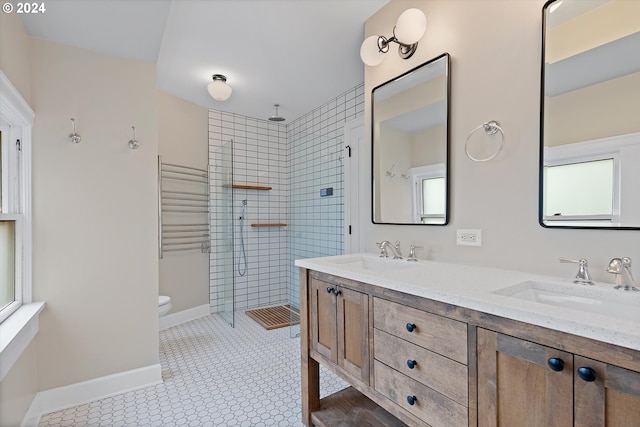 bathroom with a wealth of natural light, vanity, a tile shower, and toilet