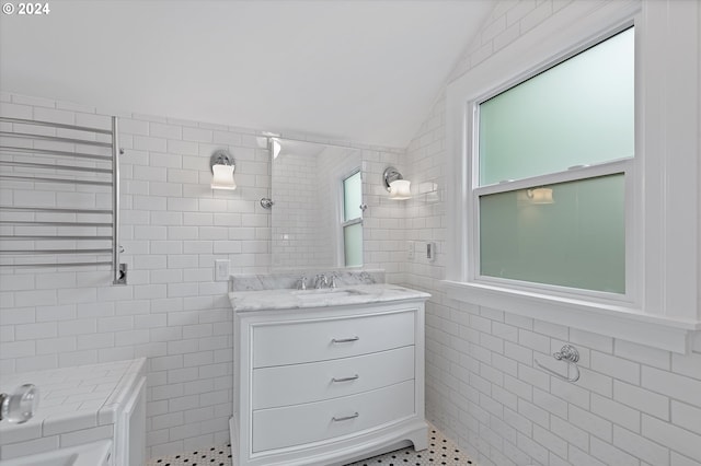 bathroom with tile patterned floors, tile walls, lofted ceiling, tiled shower, and vanity