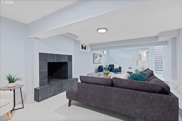 living room featuring a tiled fireplace and light carpet