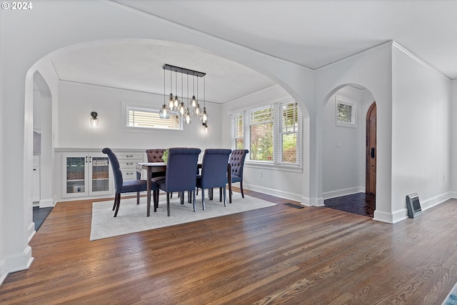 dining room with dark wood-type flooring, crown molding, and a notable chandelier