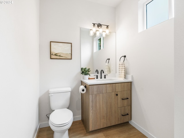 bathroom featuring vanity with extensive cabinet space, toilet, and wood-type flooring