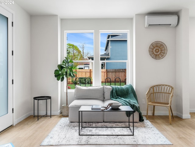 living area with an AC wall unit, light hardwood / wood-style flooring, and a wealth of natural light