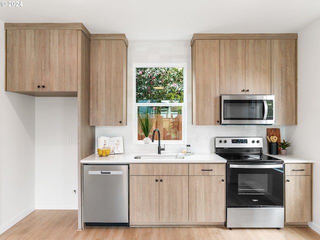 kitchen featuring appliances with stainless steel finishes, sink, light wood-type flooring, and light brown cabinets