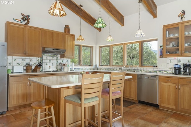 17252 N Applegate Rd, Grants Pass, OR 97527 - kitchen featuring appliances with stainless steel finishes, under cabinet range hood, backsplash, light countertops, and a kitchen breakfast bar