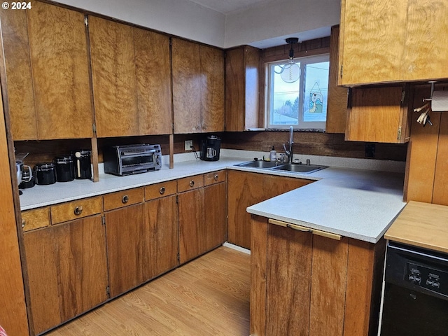 kitchen featuring dishwasher, sink, hanging light fixtures, and light wood-type flooring