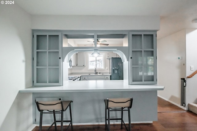 kitchen featuring a kitchen bar, sink, kitchen peninsula, and black fridge with ice dispenser