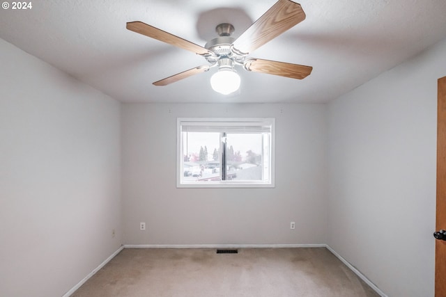 empty room featuring ceiling fan and carpet