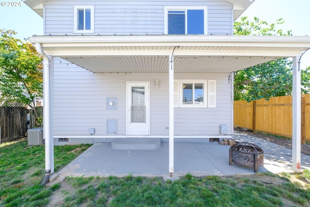 rear view of house with a patio, cooling unit, a fire pit, and a lawn