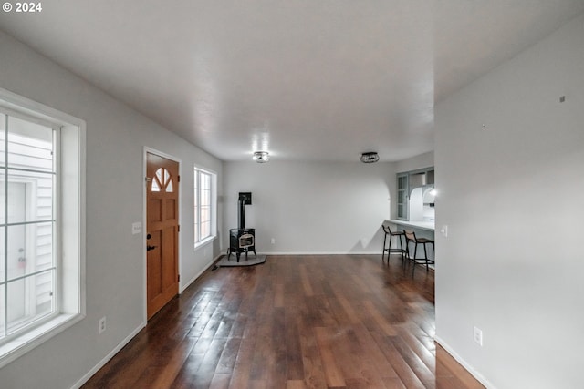 foyer entrance featuring dark wood-type flooring and a wood stove