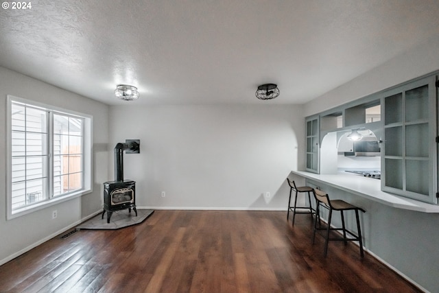 interior space with a wood stove, a textured ceiling, and dark wood-type flooring