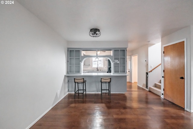 kitchen with a breakfast bar, kitchen peninsula, and dark hardwood / wood-style floors